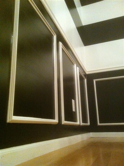 Room with black walls and white trim, featuring rectangular framed sections and a checkered black and white ceiling.