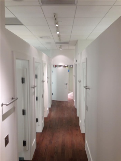 Hallway with white walls and doors, wood flooring, and track lighting on the ceiling.