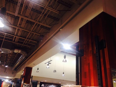 Ceiling view of an industrial-style interior with exposed beams, ductwork, and hanging lights.