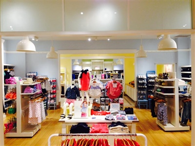 A brightly lit clothing store with neatly arranged racks and shelves displaying colorful apparel.