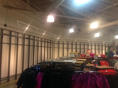 A clothing store with racks of garments and an industrial-style ceiling with exposed beams and overhead lighting.