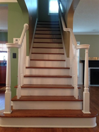 A straight staircase with wooden steps, white railings, and green walls, leading to the upper floor of a house.