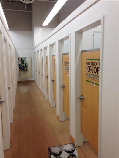 A row of fitting rooms with wooden doors and "Occupied" signs, located in a store with white walls and wooden floors.