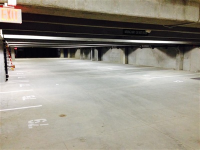 An empty concrete parking garage with low ceilings and numbered parking spaces.