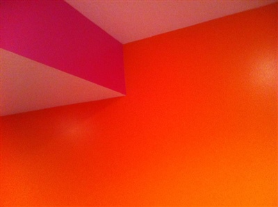 A brightly colored room with orange and pink walls and a white ceiling.