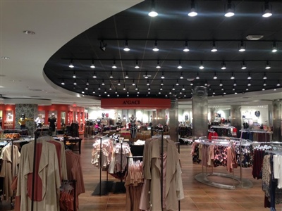 A spacious clothing store with modern lighting, neatly arranged racks of clothing, and a mix of apparel on display.