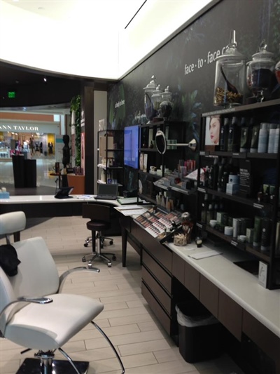 A salon interior with a variety of hair care products displayed on shelves, a white salon chair, and a counter with a mirror.