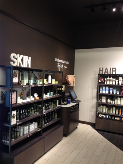 A retail display area with shelves labeled "SKIN" and "HAIR," showcasing various skincare and hair care products, along with a checkout counter.