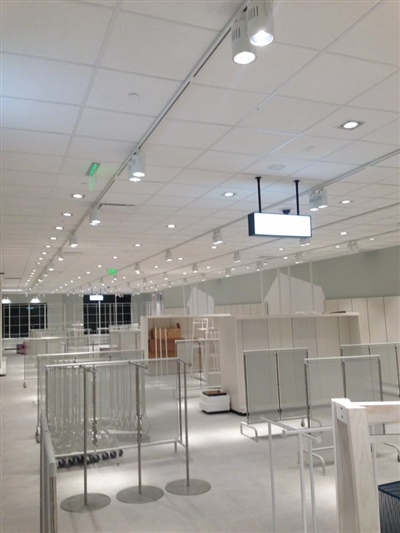 A large, well-lit store interior with empty shelves and display units, illuminated by ceiling lights.