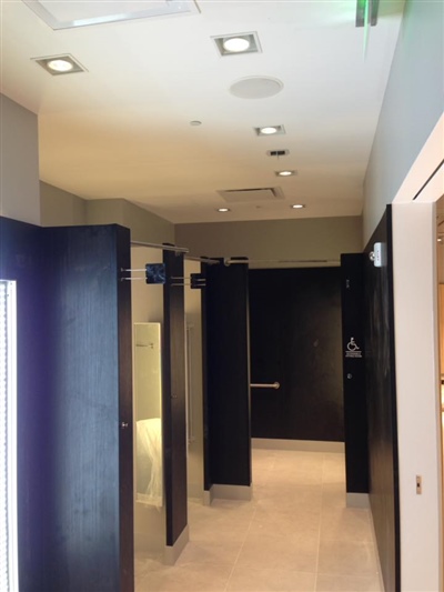 A hallway with multiple fitting rooms, featuring dark doors and ceiling lights, in a modern retail store.