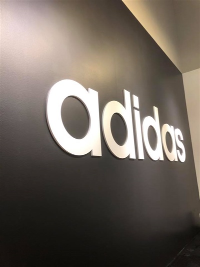 A black wall with the white "adidas" logo prominently displayed.