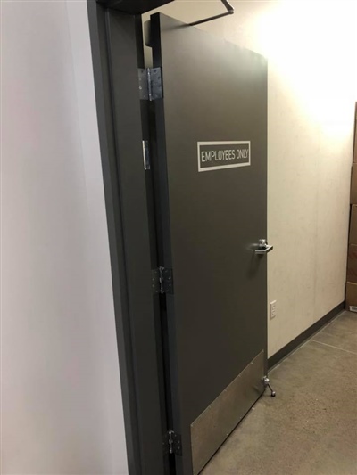 A gray door labeled "Employees Only" in a well-lit hallway.