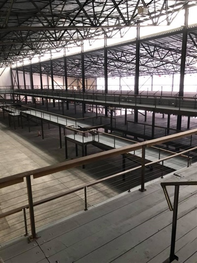 A large, empty industrial warehouse with multiple levels, metal railings, and a high, partially transparent roof.