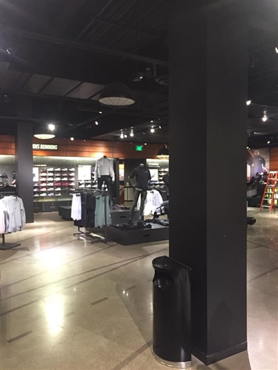 A retail store interior with clothing displays, black pillars, and dim lighting.