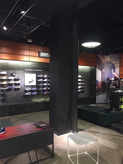 A retail store interior with shoe displays on the walls, a black pillar, and dim lighting.