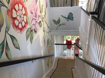 Staircase with a floral and butterfly mural on the walls, featuring pink and red flowers and green leaves.