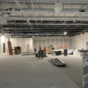 Wide view of the Eagan retail store interior during bar joist ceiling painting and drywall construction