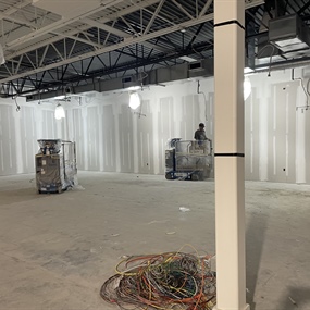 Painters working from lifts on commercial retail walls beneath a black exposed ceiling in Eagan, Minnesota