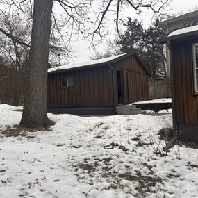 Weathered cedar siding on a 1950s lakeside cabin before wood repairs and solid-body staining