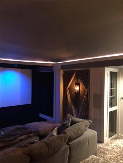 A cozy home theater with a large screen, ambient lighting, and a comfortable sectional sofa.